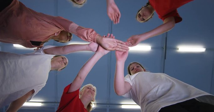 4k, School kids stacking hands in basketball court at school gym.