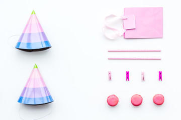 Birthday party accessories. Party hat, sweets, paper bag for gift on white background top view copy space pattern