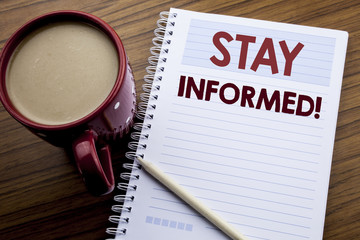 Hand writing text caption inspiration showing Stay Informed. Business concept for Be Awareness Or Awake written on note paper notepad book on the wooden background with coffee and pen.