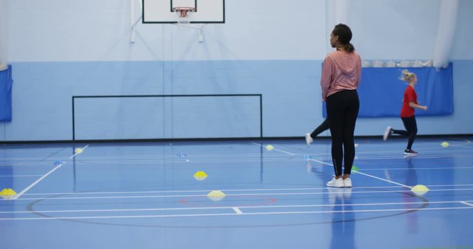 4K Sports teacher watching over children as they exercise in P.E. class