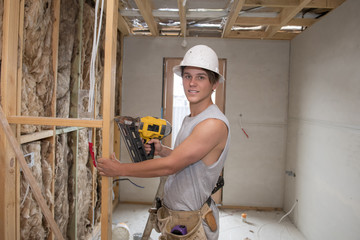 young builder industry trainee man on his 20s wearing protective helmet learning working with drill at industrial workshop site