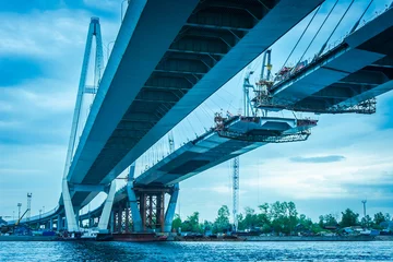 Fototapeten Bau einer Brücke über den Fluss. Die lange Brücke. Metallkonstruktionen. Hohe Brücke. Autobahnbau. © Grispb