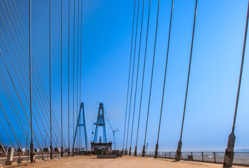 Construction of the bridge. The bridge on the cables. Metal structures. The long bridge. Designing bridges. Metal structures against the blue sky.