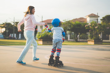 Asian mother helping her son to playing roller skate in the park
