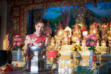 Asian woman wearing chinese dress, smile in chinese new year, Chinese woman dress traditional cheongsam at Chinese Temple.