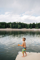 Little boy standing on dock fishing in a lake