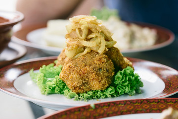 Vegetarian dinner table. Plate with black quinoa and oatmeal cutlets with prunes on white wooden table close up