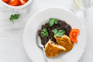 Vegetarian dinner table. Plate with black quinoa and oatmeal cutlets with prunes on white wooden table close up