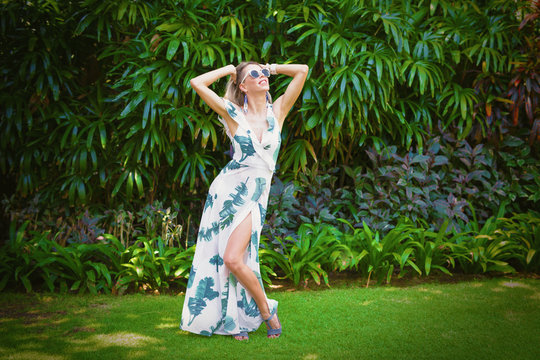 Woman in summer dress posing on green foliage background