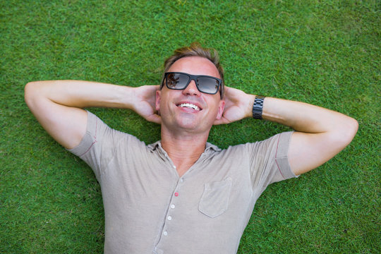Young man lying down in green grass