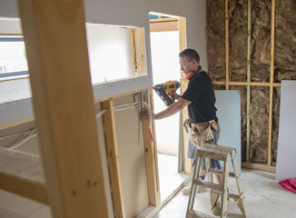 attractive and confident constructor carpenter or builder man working wood with electric drill at industrial construction site