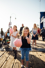 Three daughters and a father walking on Santa Monica Pier eating cotton candy