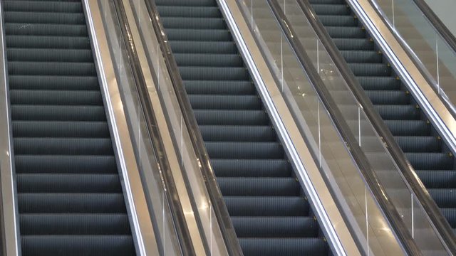 Close up three parallel escalator staircases and handrails moving up and down in an abandoned office building