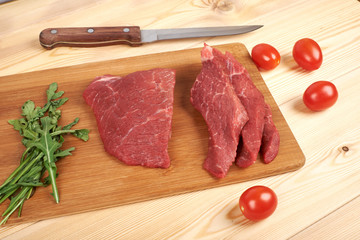 Sliced raw beef on cutting board and vegetables