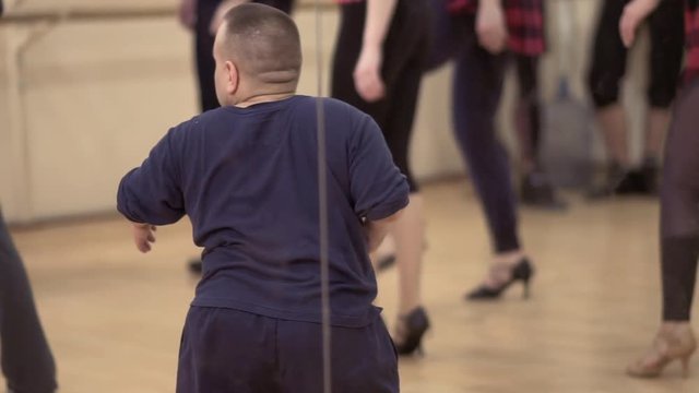 Adult dwarf man dance together with friends in the studio