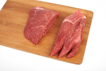 Raw beef piece and slices on wooden cutting board isolated on white background