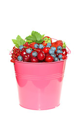 Berry season. pink bucket with berries of strawberries, blueberries, cherries, red currants isolated on white background. Harvest of berries. Delicious ripe berries in a pink bucket