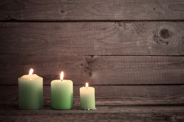 green candles on dark wooden background
