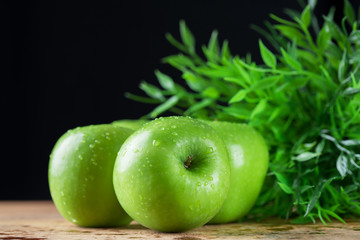 Green apple with water drop on wood table