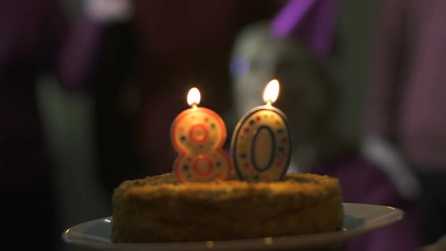 Friends presenting birthday cake to smiling senior lady, celebration atmosphere