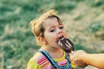 Funny little girl with ice cream . The girl was stained with a sweet dessert