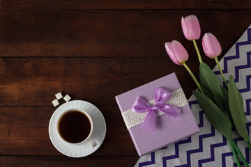 Tulips, Gift, Cup with Coffee on Dark Wooden Background. Flat, top view
