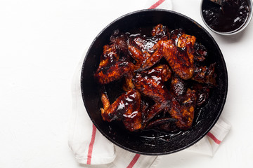 Chicken wings with sauce on white background with red striped towel. Summer barbeque concept.