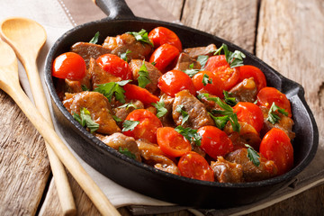 Organic food: beef in spicy sauce with tomatoes and greens close-up on a frying pan. horizontal