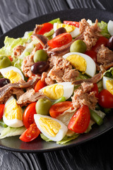 Classic French nicoise salad with fresh vegetables, eggs, tuna and anchovies close-up. vertical