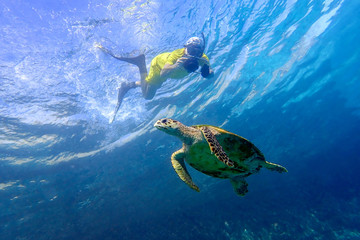 Man snorkeling with sea turtle in the tropical water of Maldives