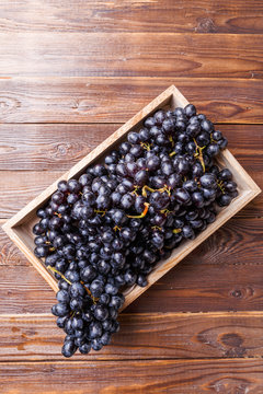 Image of black grapes in wooden box on table