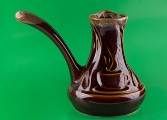 Black coffee in the jezve old brown clay and coffee beans around it on a green chroma key as the...