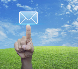 Hand pressing mail flat icon over green grass field with blue sky, Contact us concept