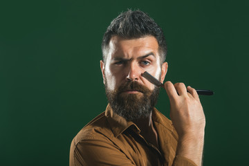 Portrait brutal caucasian hipster, unshaven man with vintage straight razor. Hairstylist with vintage straight razor. Hairdresser shaving with straight razor.