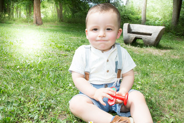 Little boy sitting on grass in green forest in summer have nice day. Childhood, nature and happiness concept