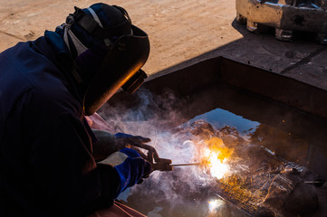 Industrial Worker labourer or welder at the Manufacturing factory welding metal or steel structure. Hot Work safety or Welding safety with masks and gloves to protect lights and sparks
