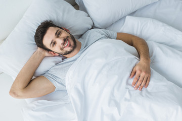 top view of cheerful man lying on bed in the morning