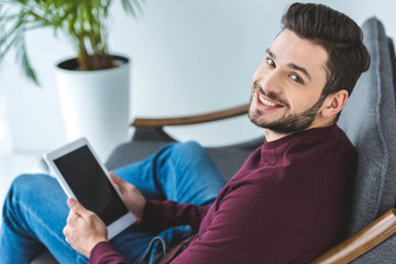 cheerful handsome bearded man using digital tablet at home