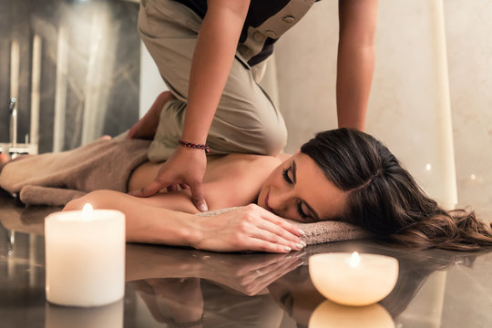 Young woman lying down while enjoying the acupressure techniques of traditional Thai massage at luxury spa and wellness center