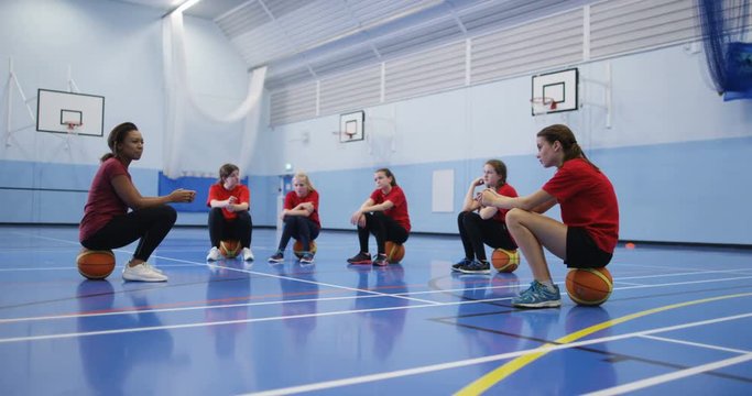 4k, A female African American coach talking to a group of teenage girls during a physical education class.
