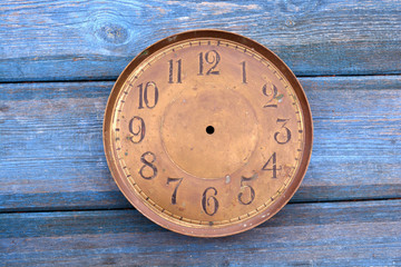 Antique brass clock face  on  blue wooden background