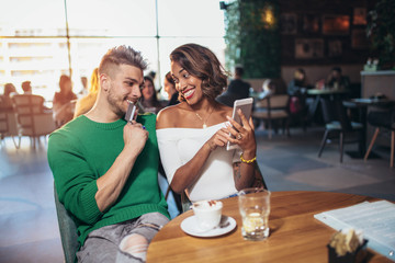 Two happy mixed race couple having fun at the coffee shop using digital tablet and credit card for online shopping.