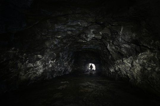 man in a dark cave watch out of the exit - depression concept