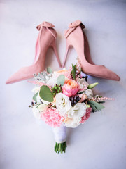 Bride's dust pink shoes lie on the floor with pink wedding bouquet