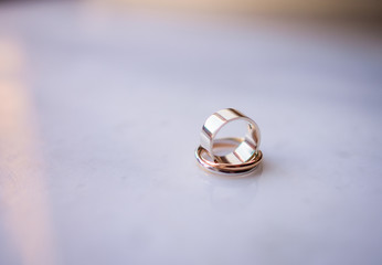 Golden wedding rings stand on each other on white marble table