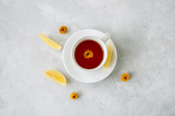 A cup of flower tea with lemon on a white stone background. Still life.