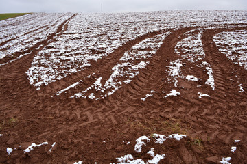 Autumn plowed  field with tractor traces and first snow
