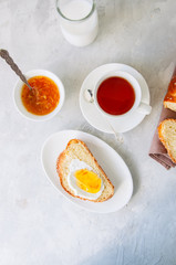 Slice of homemade sesame seeds challah bread  with jam, glass of milk and a cup of tea on a white background.