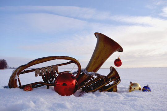 brass musical wind instrument on snow and Christmas baubles