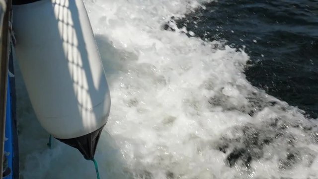 Slow motion of a boat with a bouy cruising through ocean water